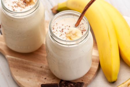 Banana smoothie in a glass jar with bananas
