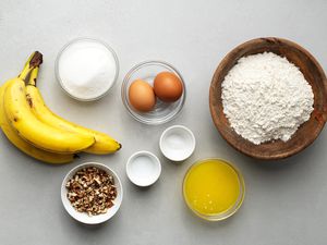 Ingredients for banana bread in bowls on grey surface