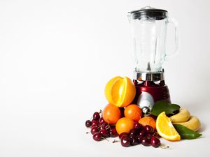 A blender surrounded by fruit