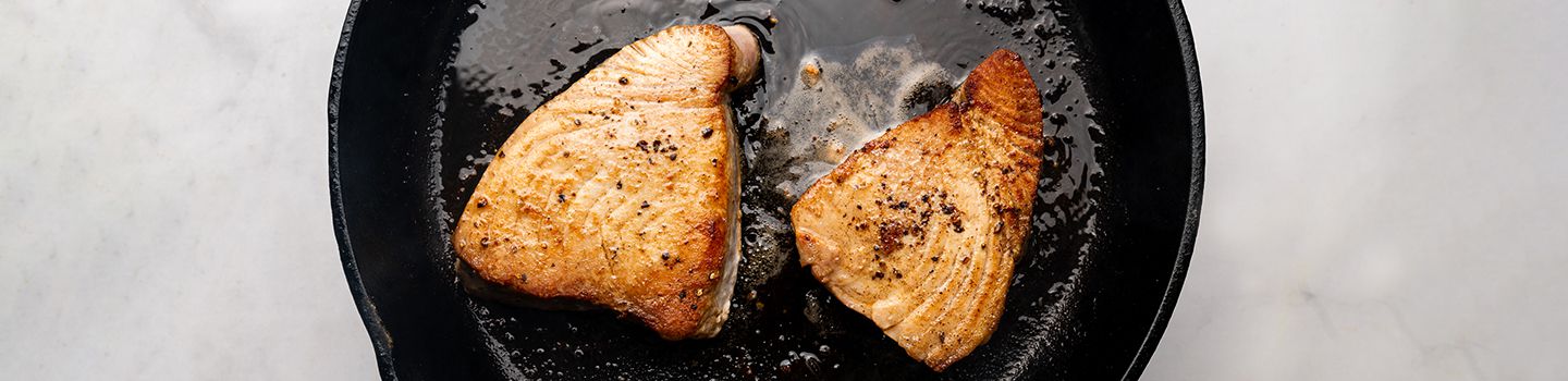 Tuna steaks being seared in a cast iron skillet