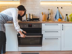 woman using oven in home kitchen