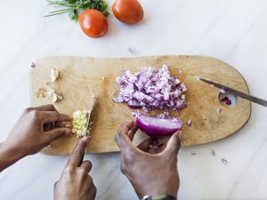 Hands of Black man and woman chopping onion and garlic