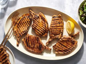 Greek-Style grilled pork chops with marinade on a white platter