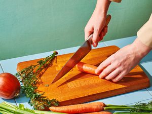 Person cutting a carrot on a wooden cutting board
