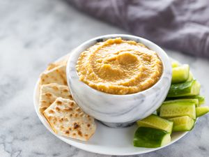 Low-fat oil free tahini free hummus in a bowl with crackers and cucumbers on a plate