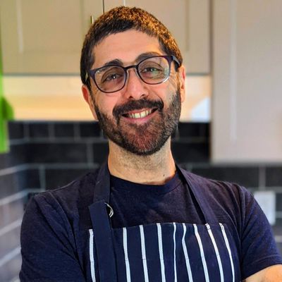 Headshot of Omid Roustaei in kitchen wearing a striped apron