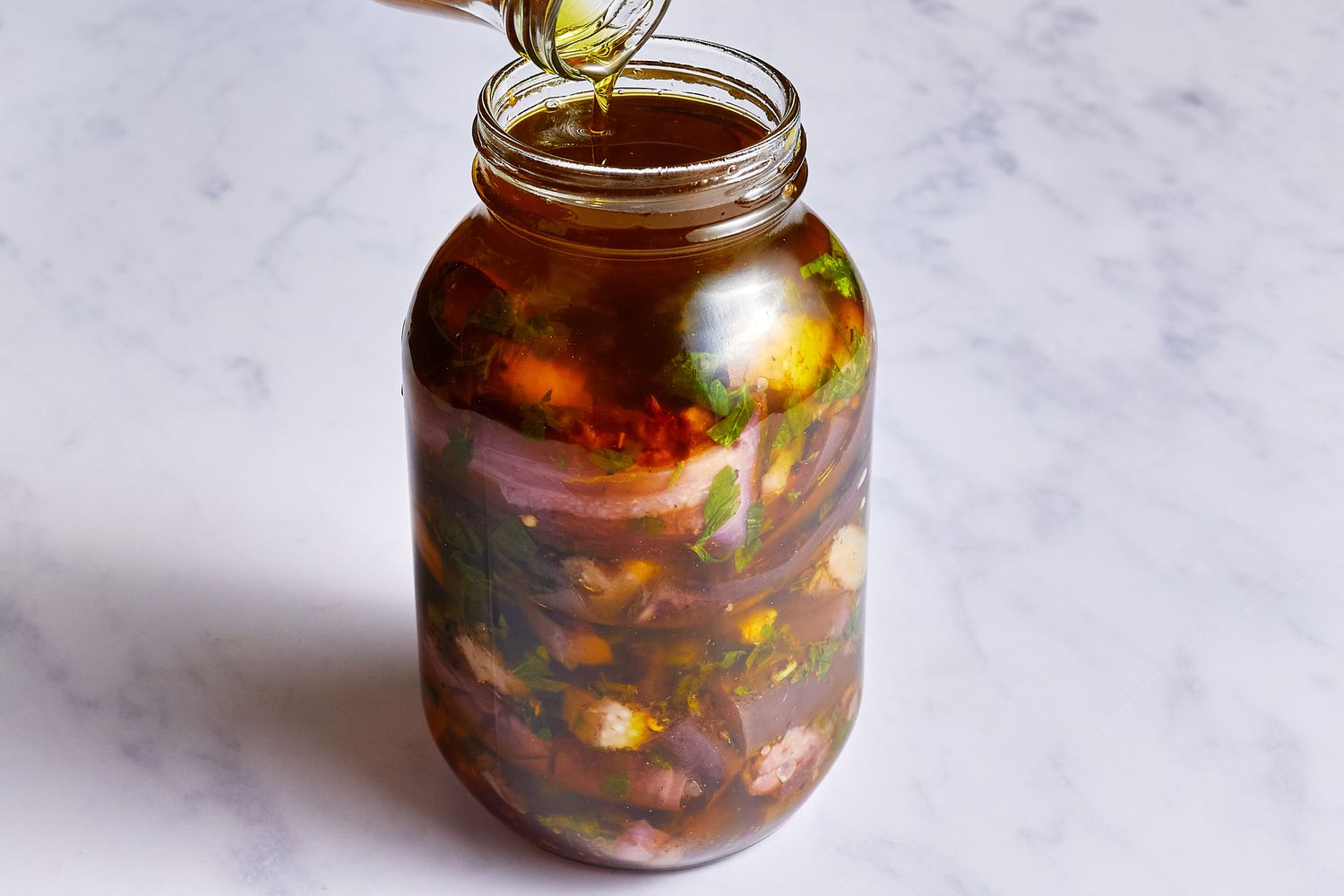 Oil being poured over eggplant mixture in the jar