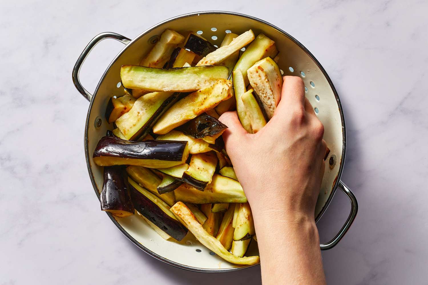 Eggplant being squeezed in the colander 