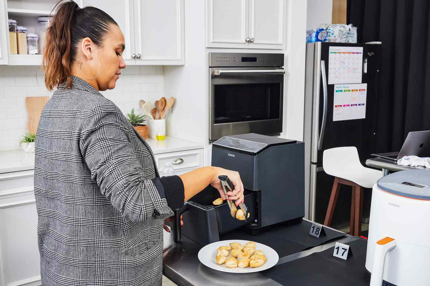 A person grabbing food with tongs out of the Cosori Dual Blaze Smart Air Fryer