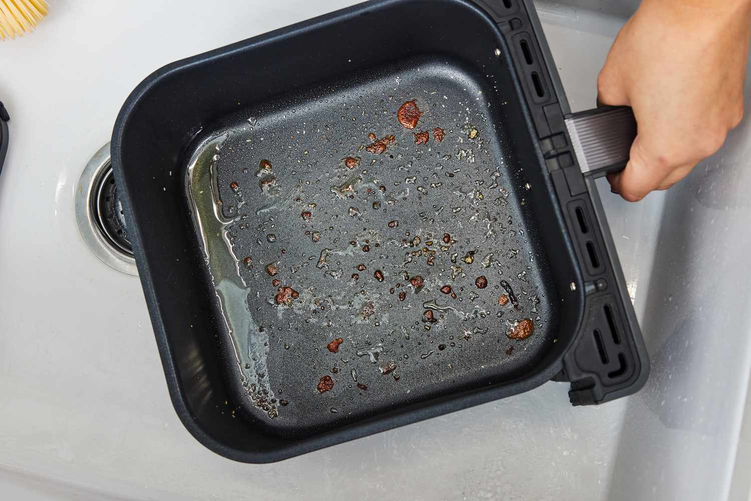 Hand holding the dirty basket from the Cosori Dual Blaze 6.8-Quart Smart Air Fryer