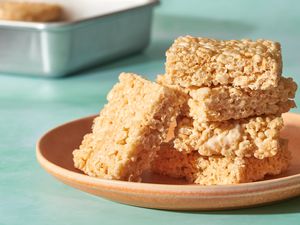A plate of rice crispy treats with a pan of rice crispy treats in the background