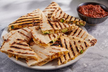 A plate with grilled zucchini and corn quesadillas, served with salsa