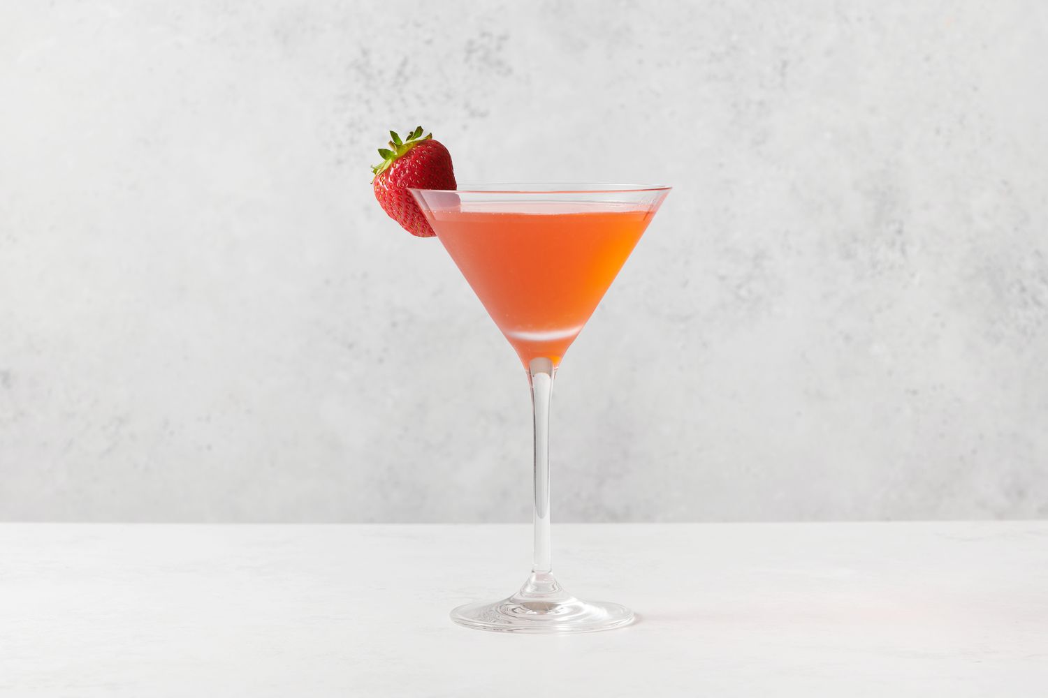A strawberry martini garnished with a whole strawberry