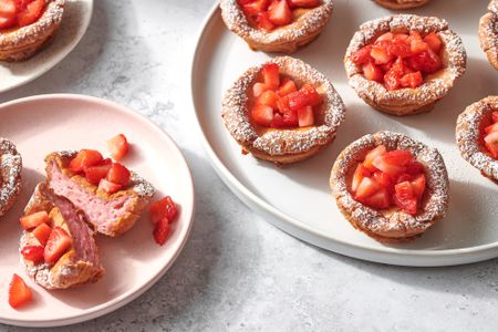 A plate of strawberry miso mochi muffins topped with chopped strawberries and confectioner's sugar