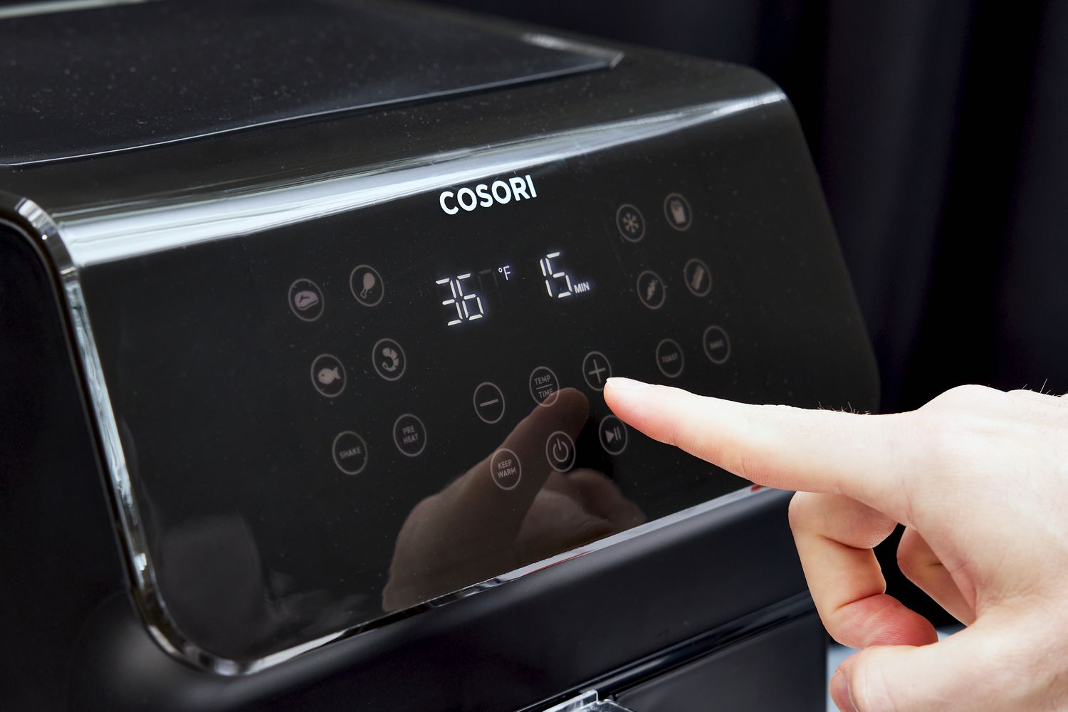 Hand pushing buttons on the Cosori VeSync Pro II Smart Air Fryer