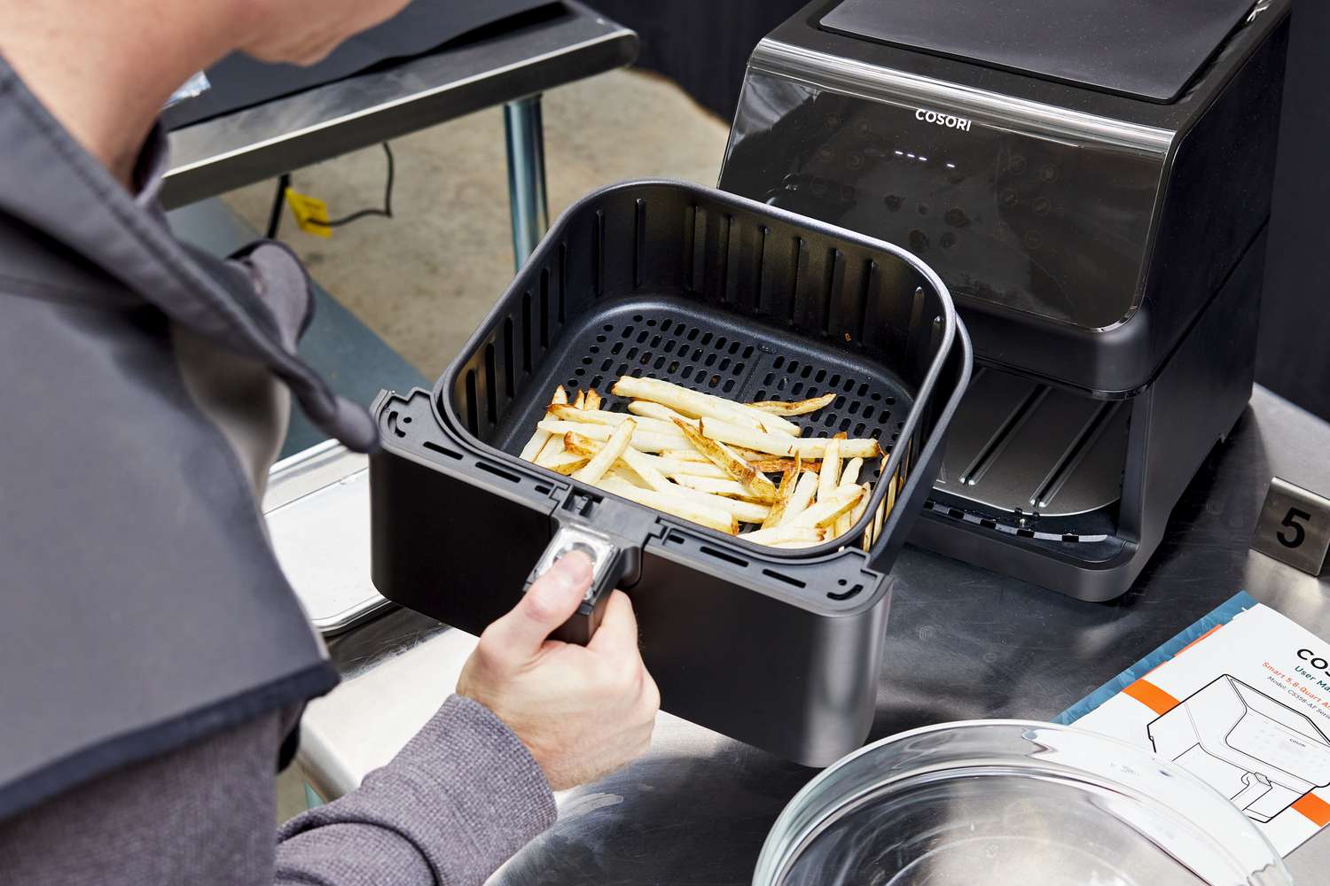 A person holding a basket of french fries from the Cosori VeSync Pro II Smart Air Fryer