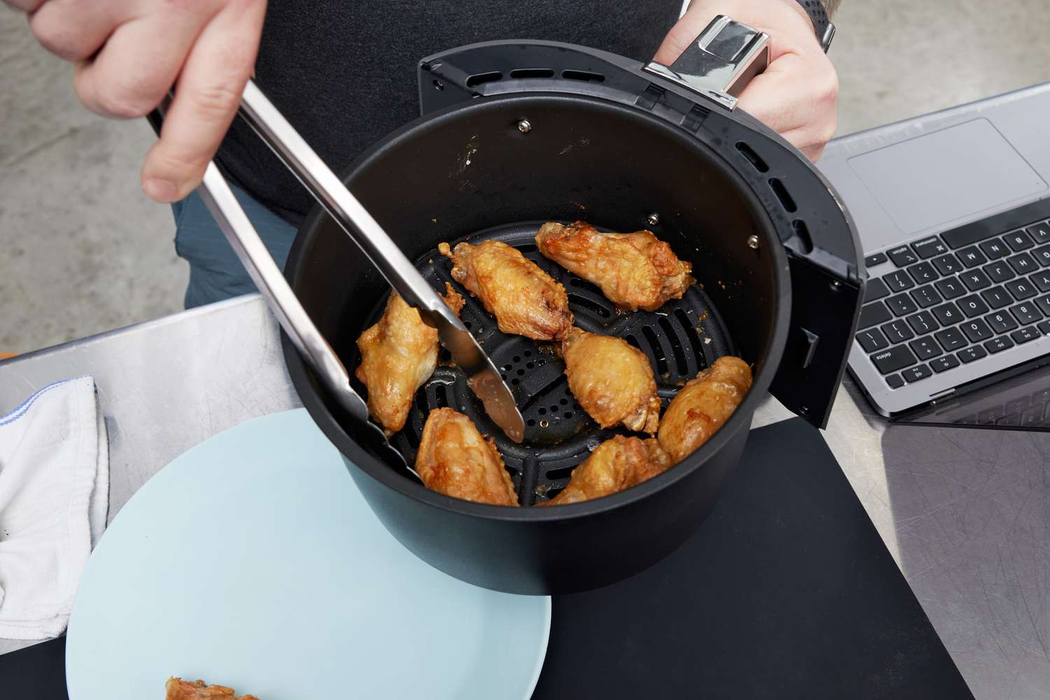 Person holding a basket of chicken wings from the Ninja 4-Quart Air Fryer 
