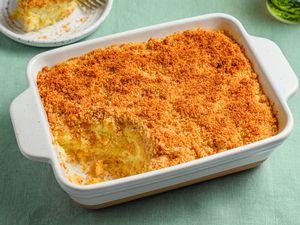 A yellow squash casserole in a large backing dish, with a plated portion of casserole