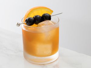 Simple amaretto sour cocktail with cherries and an orange slice garnishes