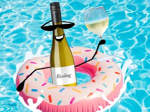 bottle of riesling in a pool float in pool holding a glass of riesling wine