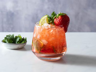 Strawberry Mojito in a glass, with mint in a small bowl 