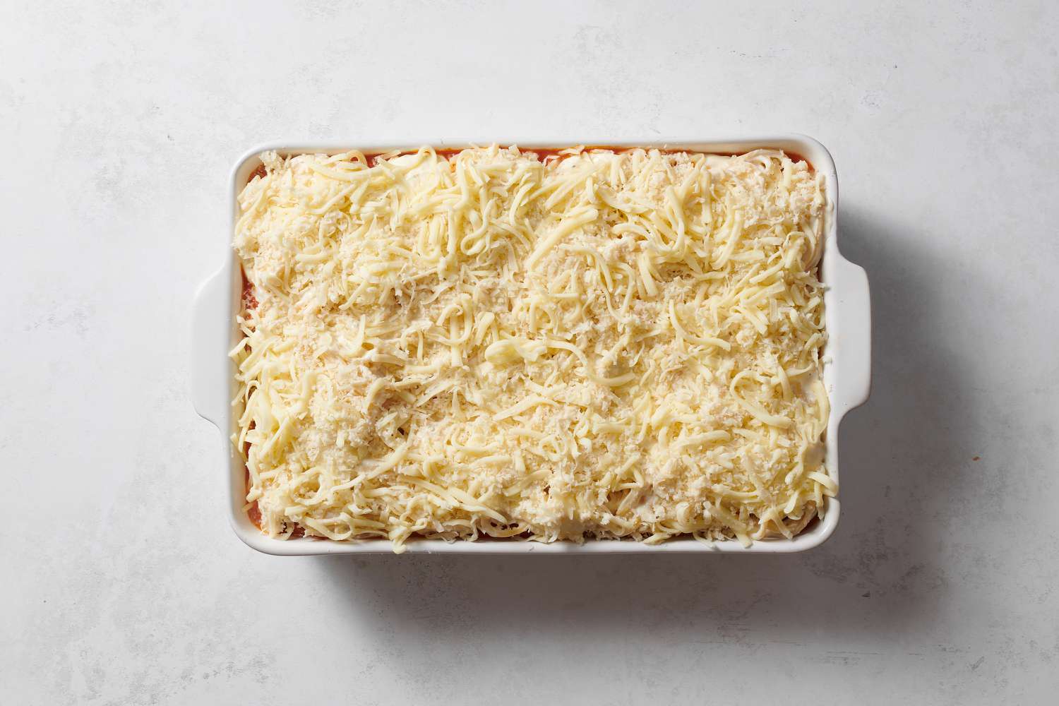 Layered pasta, meat sauce, and cheese in a baking dish
