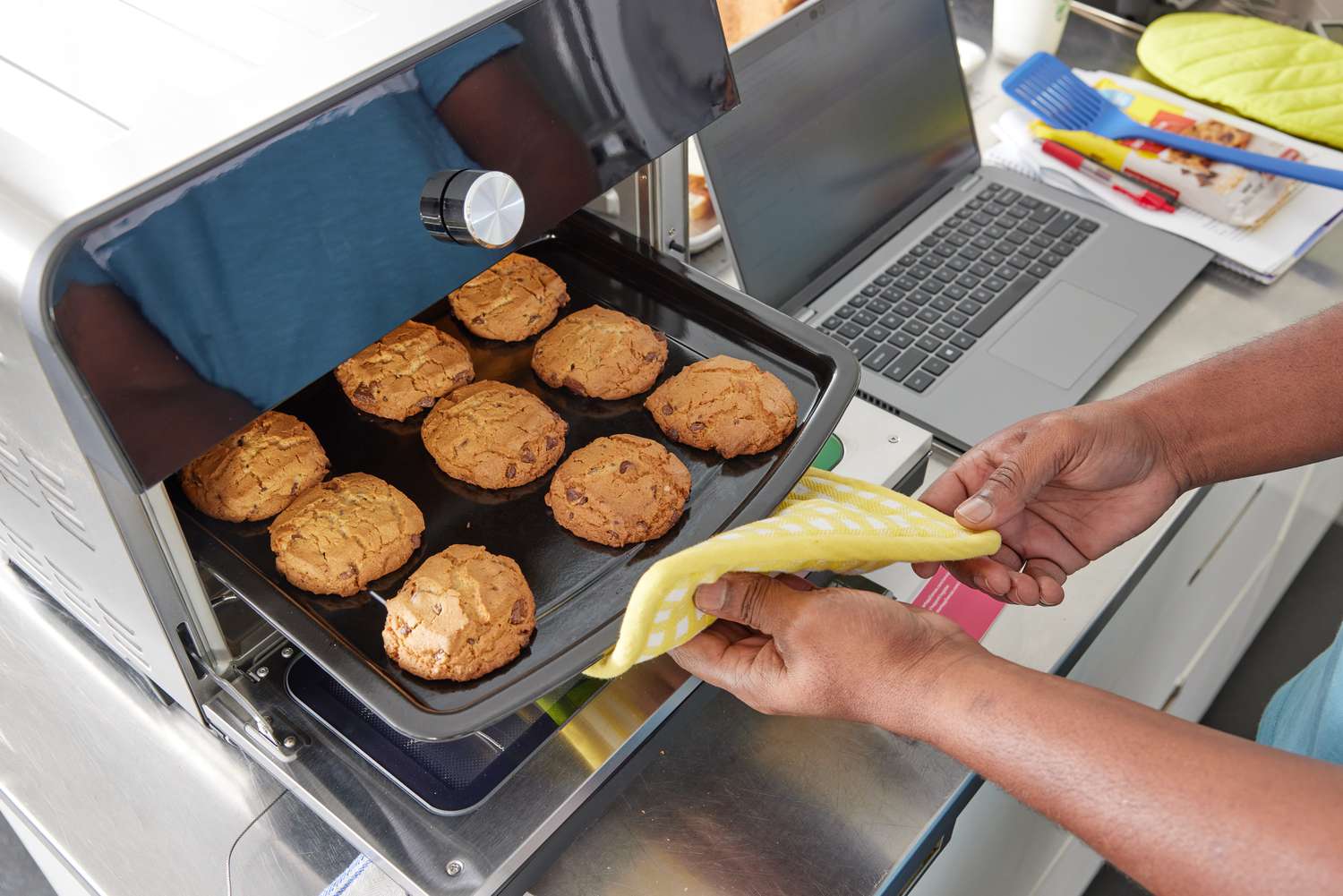 Person using pot holder to remove tray of chocolate chip cookies from Instant Omni Plus 18L Air Fryer Toaster Oven