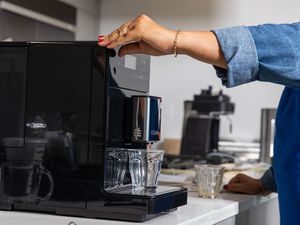 Person pressing button to dispense coffee Miele CM5300 Countertop Coffee System