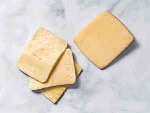 fontina cheese slices and brick of cheese on marble surface