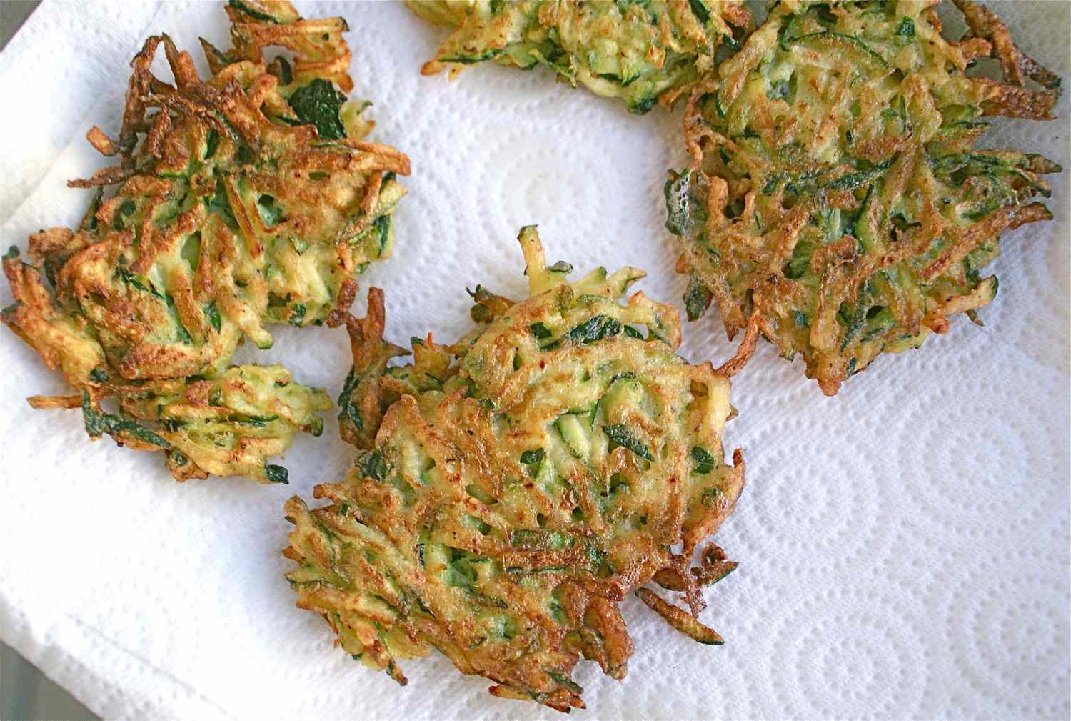 Brown and crispy zucchini fritters on a paper towel